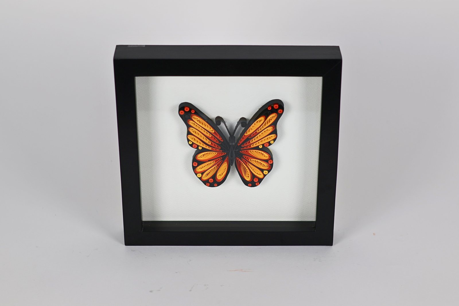 Cuadro con mariposa monarca sobre fondo claro, vista 1 de 2