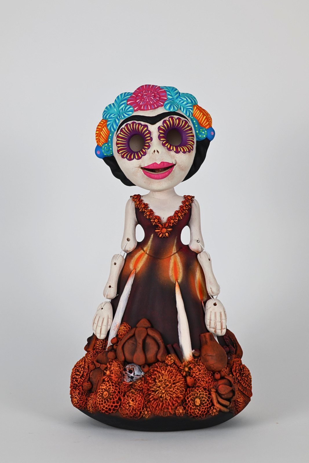 Catrina articulada con vestido café y flores naranjas, vista 1 de 3