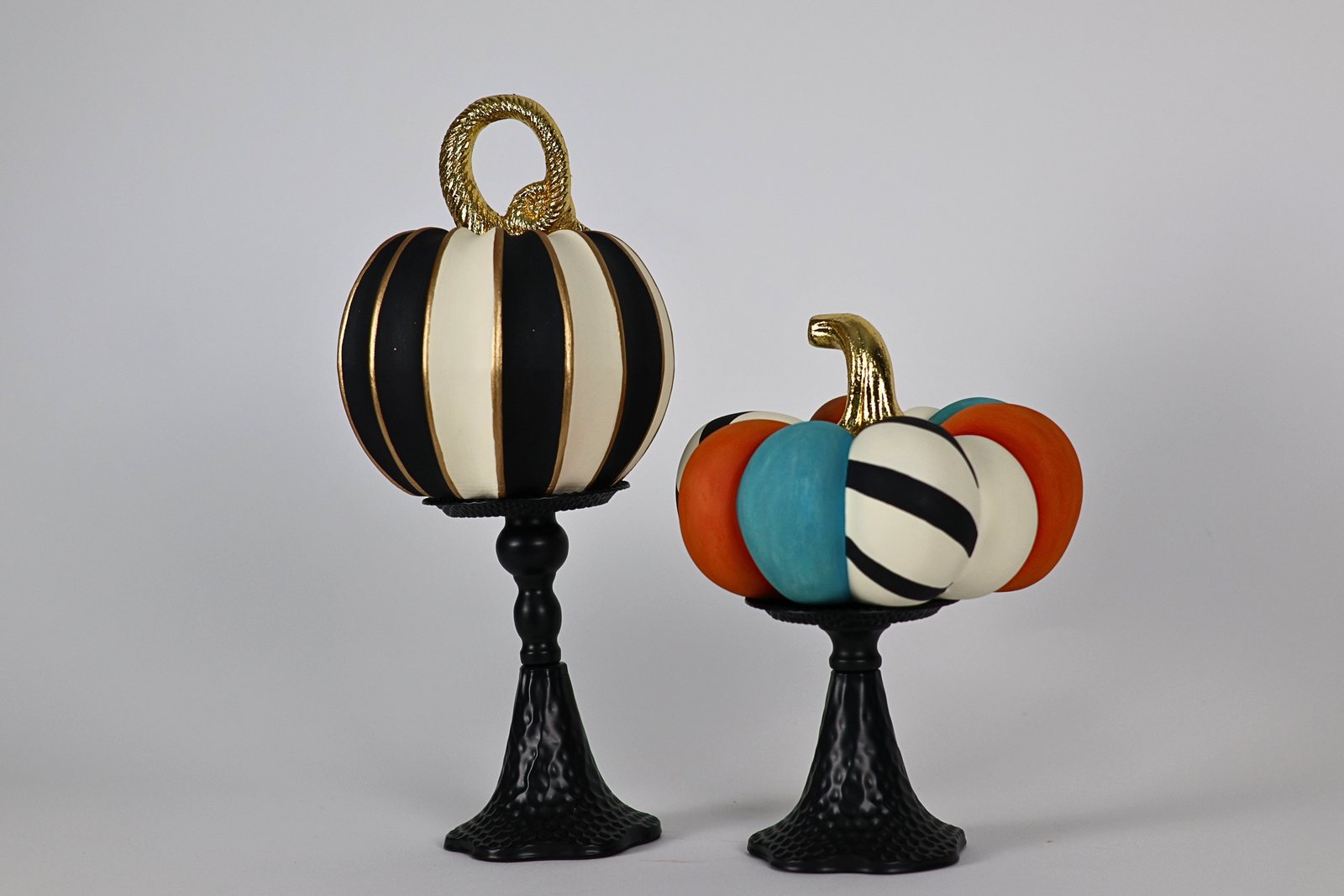 Par de calabazas decorativas sobre candelabros negros, vista 1 de 3