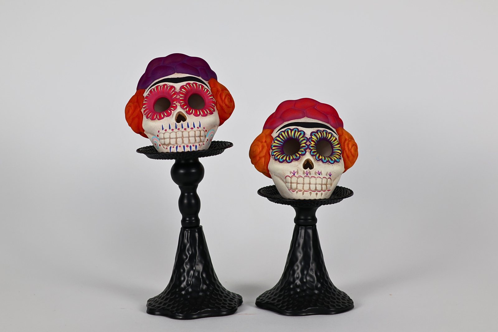 Dos calaveritas con boinas de color sobre bases negras, vista 1 de 3